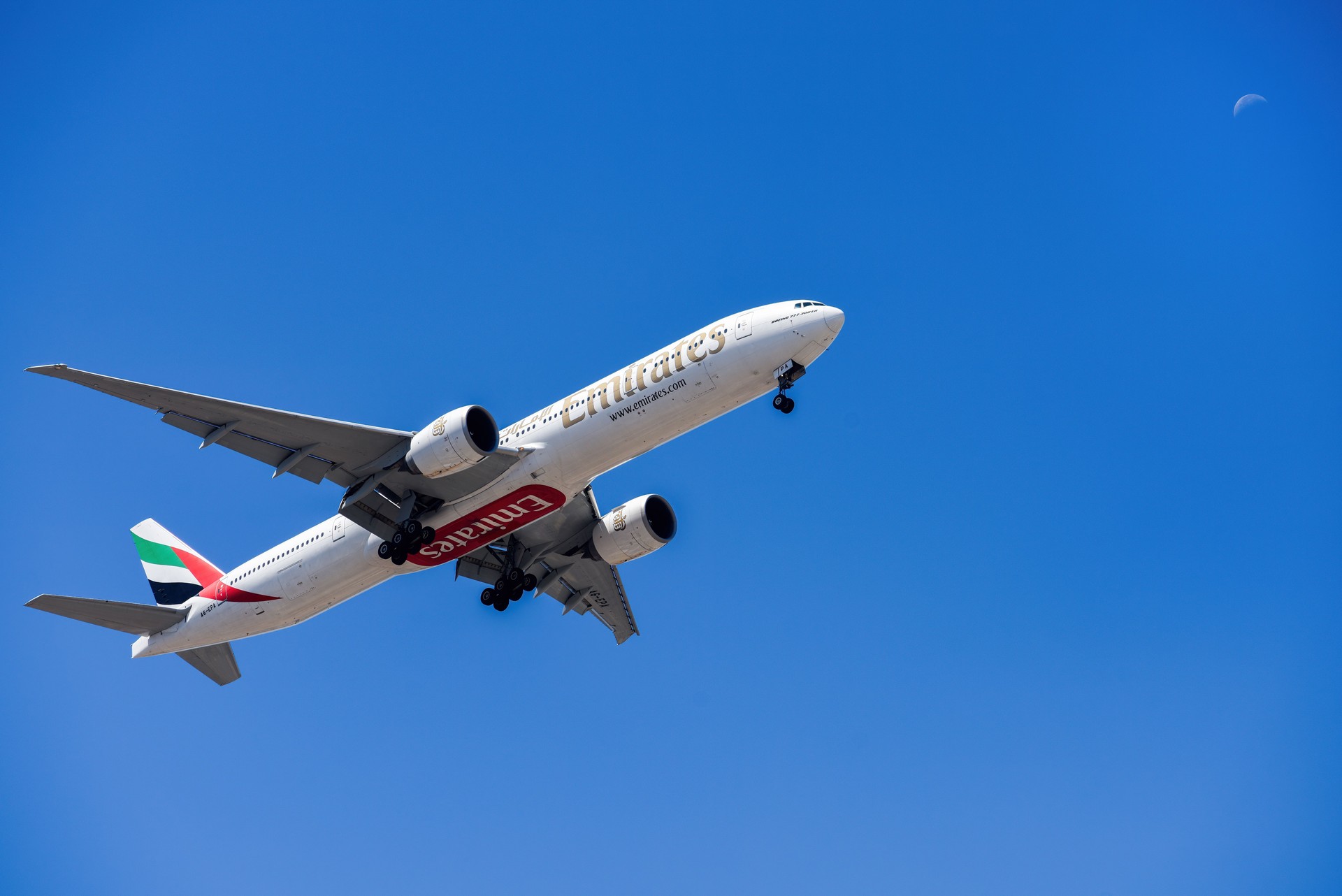 UAE based air company Emirates with aircraft Boeing 777-300ER approaching to land at Lisbon International Airport against blue sky